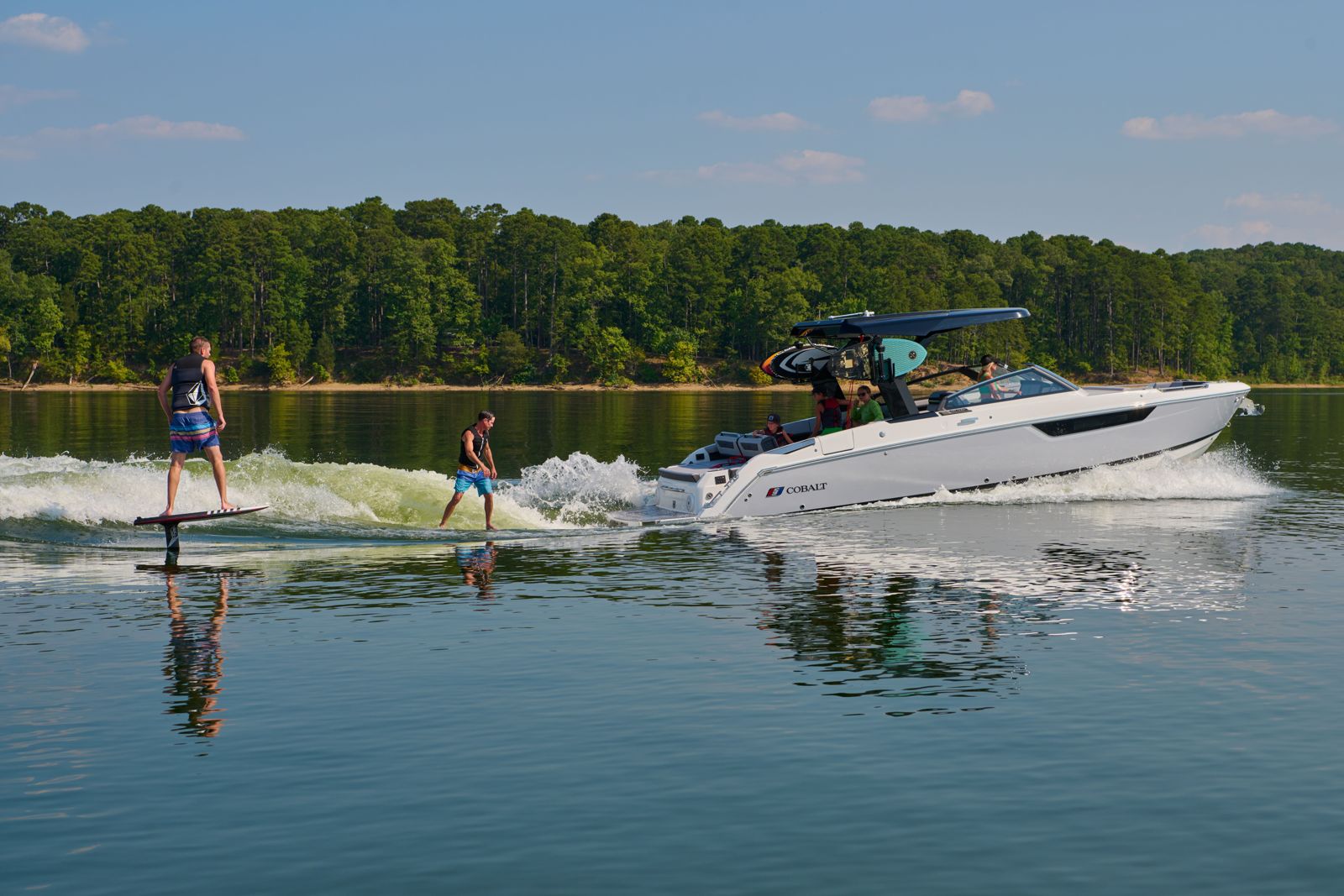 Two wakesurfers behind a Cobalt with the family on board